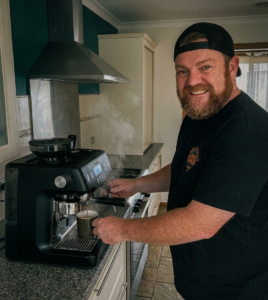 Man pulling espresso shot on Breville Oracle BES980 home espresso machine in kitchen
